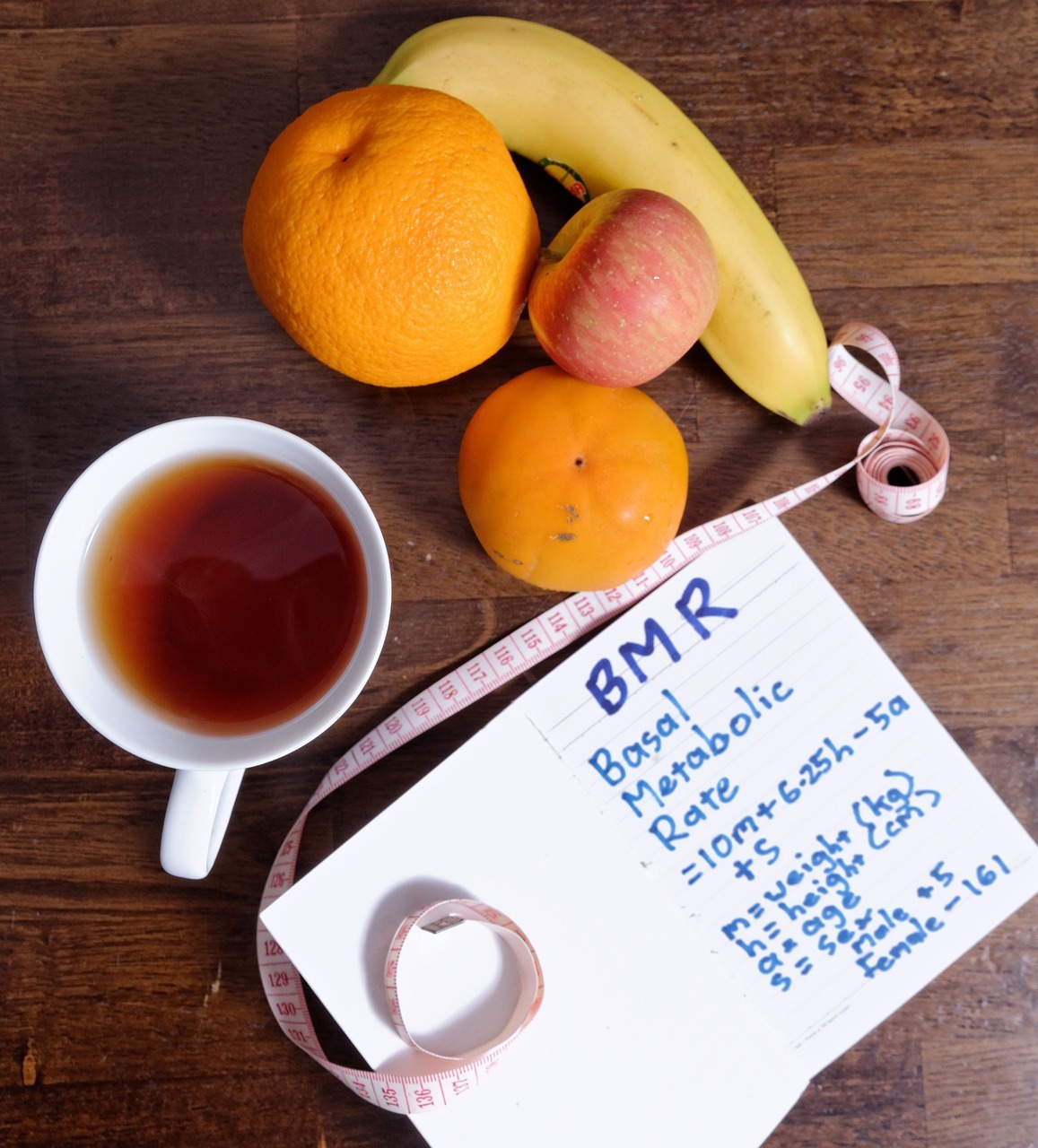 tape measure, fruits and cup on a table