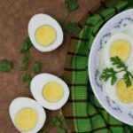 Sliced boiled eggs on a white plate with green parsley leaves