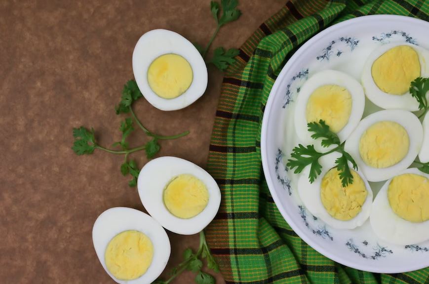 Sliced boiled eggs on a white plate with green parsley leaves