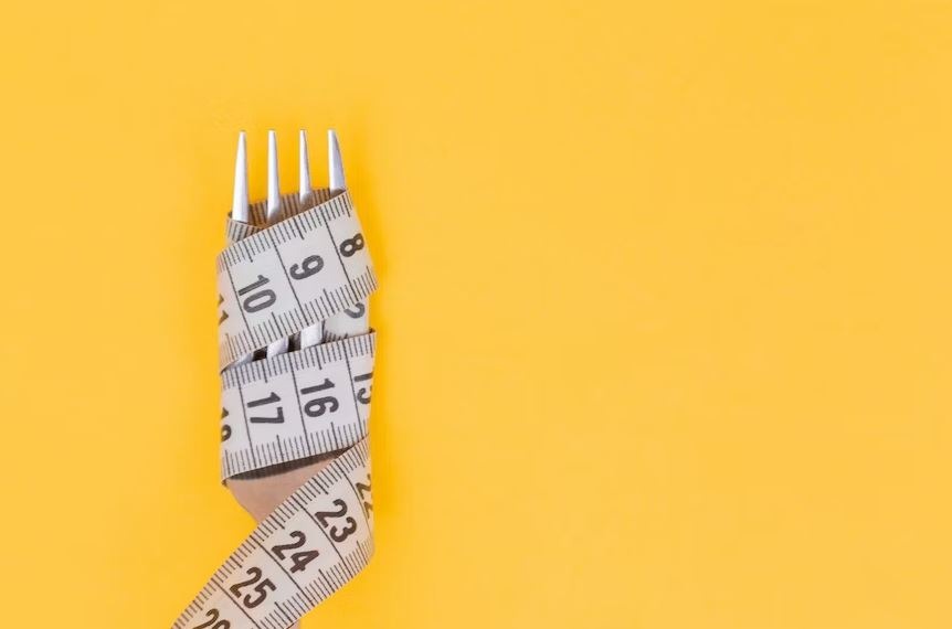 tape measure and fork with a yellow background